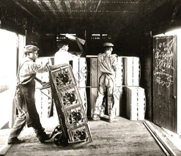 Historical photo of workers loading fruit crates into a rail car